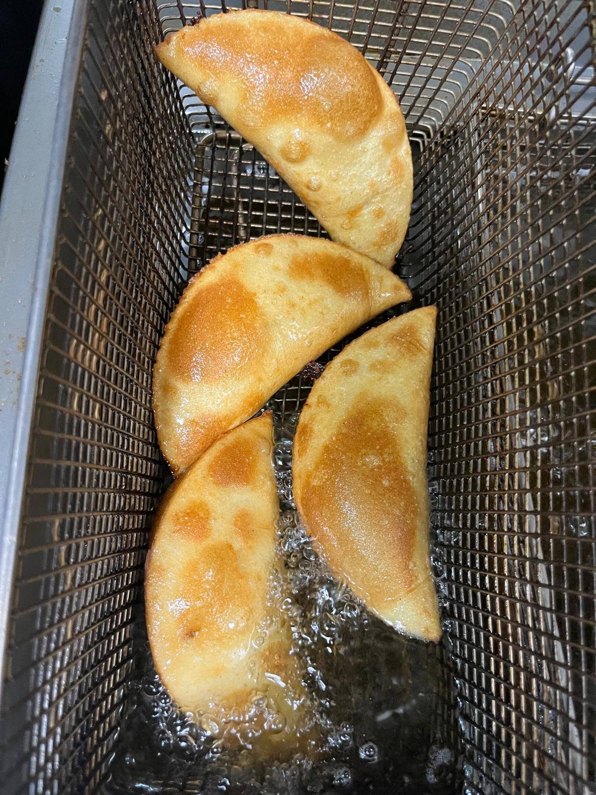 Golden empanadas draining in the fryer basket