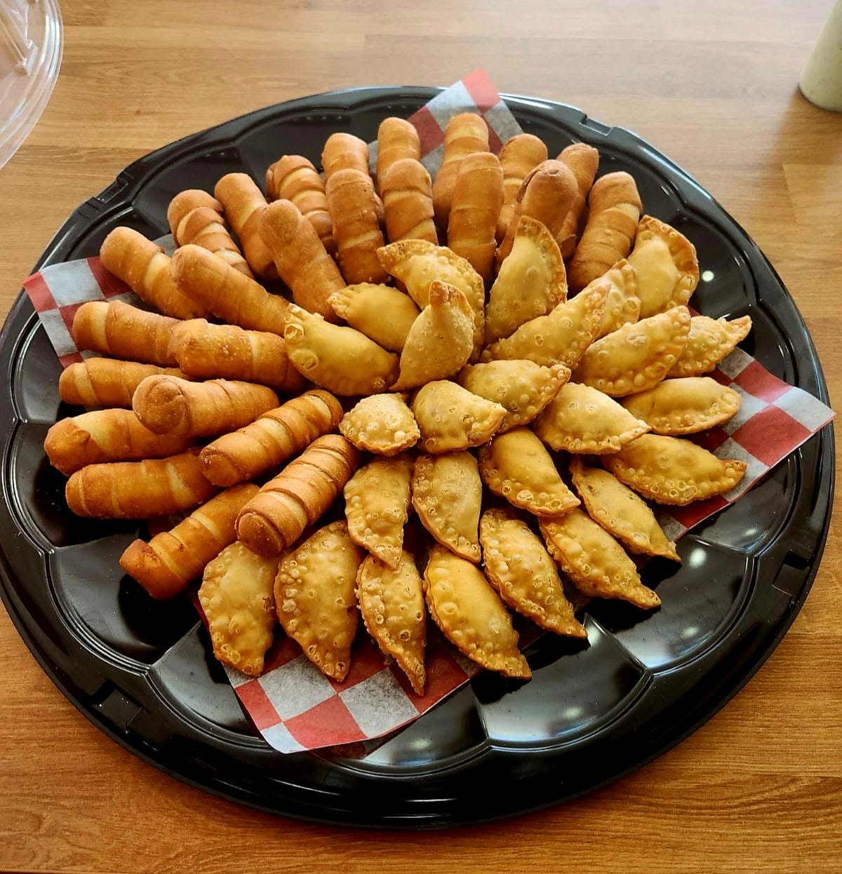 Overhead view of a 1Chick 1Bro platter of tequeños and empanadas fanned like a sunflower