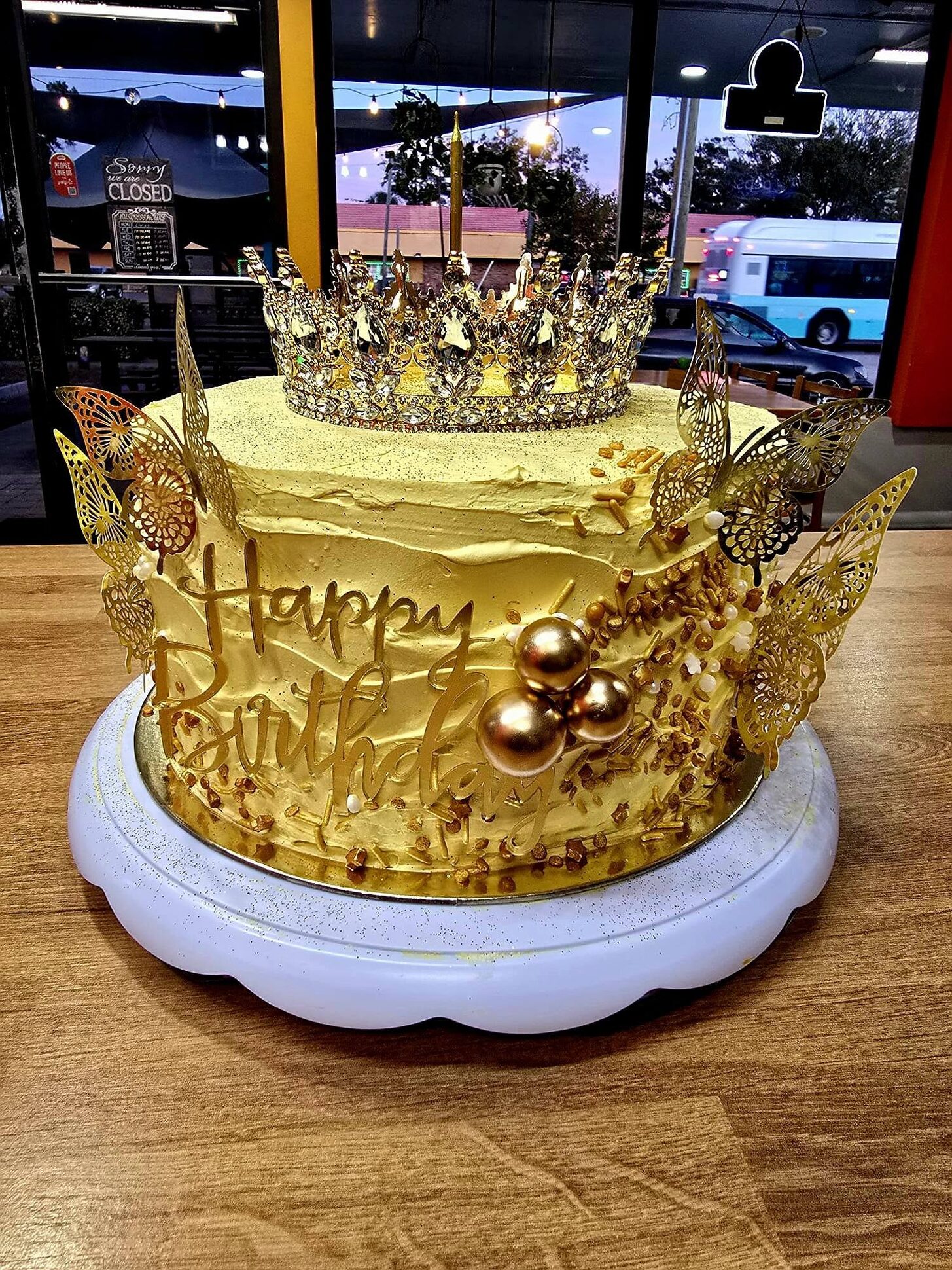 A 1Chick 1Bro crown birthday cake by the front window at dusk