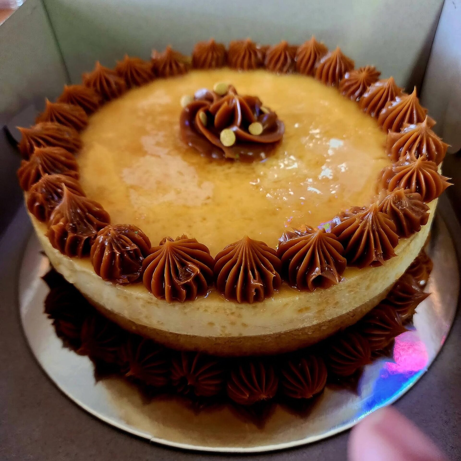 Caramel-topped custard cake with a piped chocolate rim, boxed for pickup