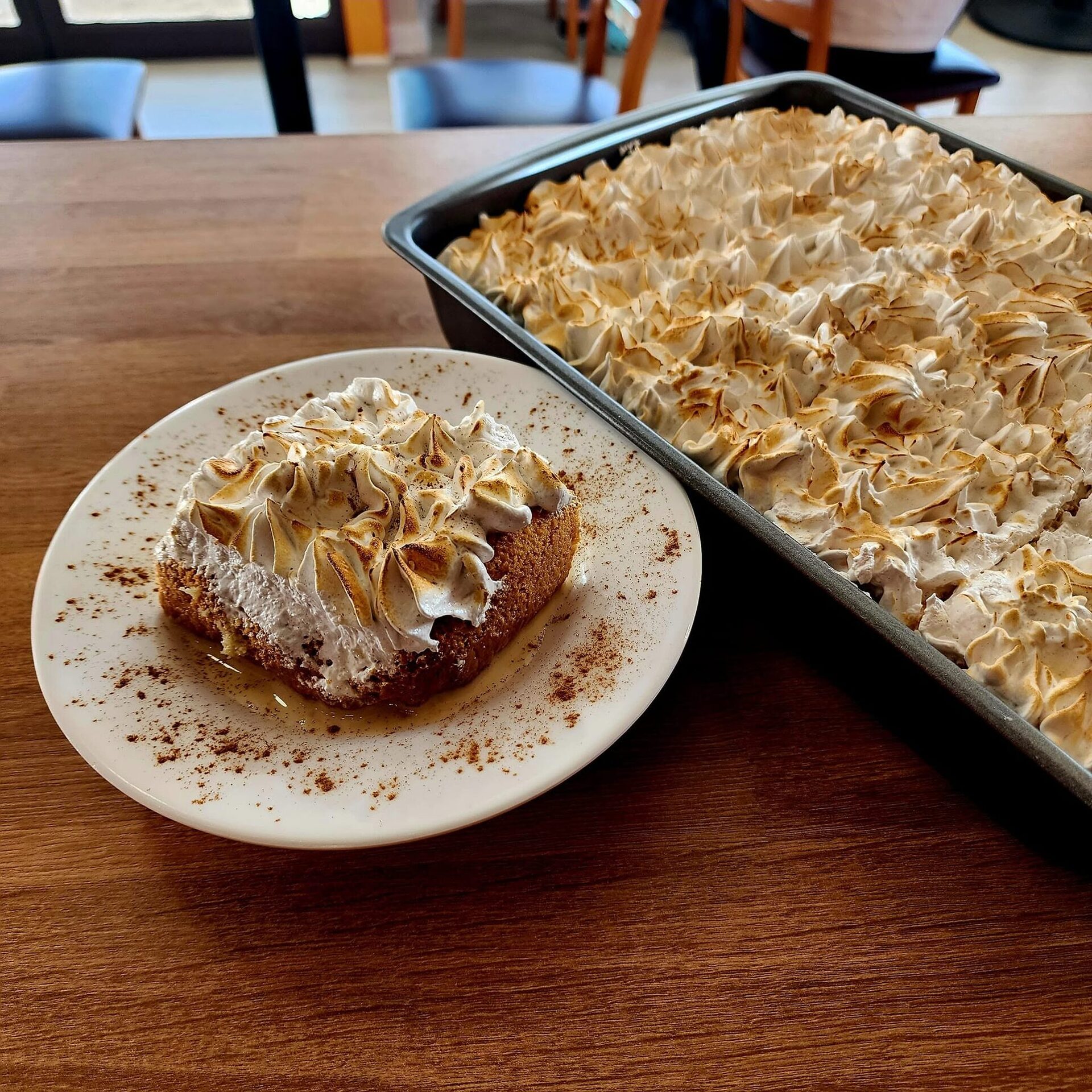 Tres leches with torched meringue beside the full pan