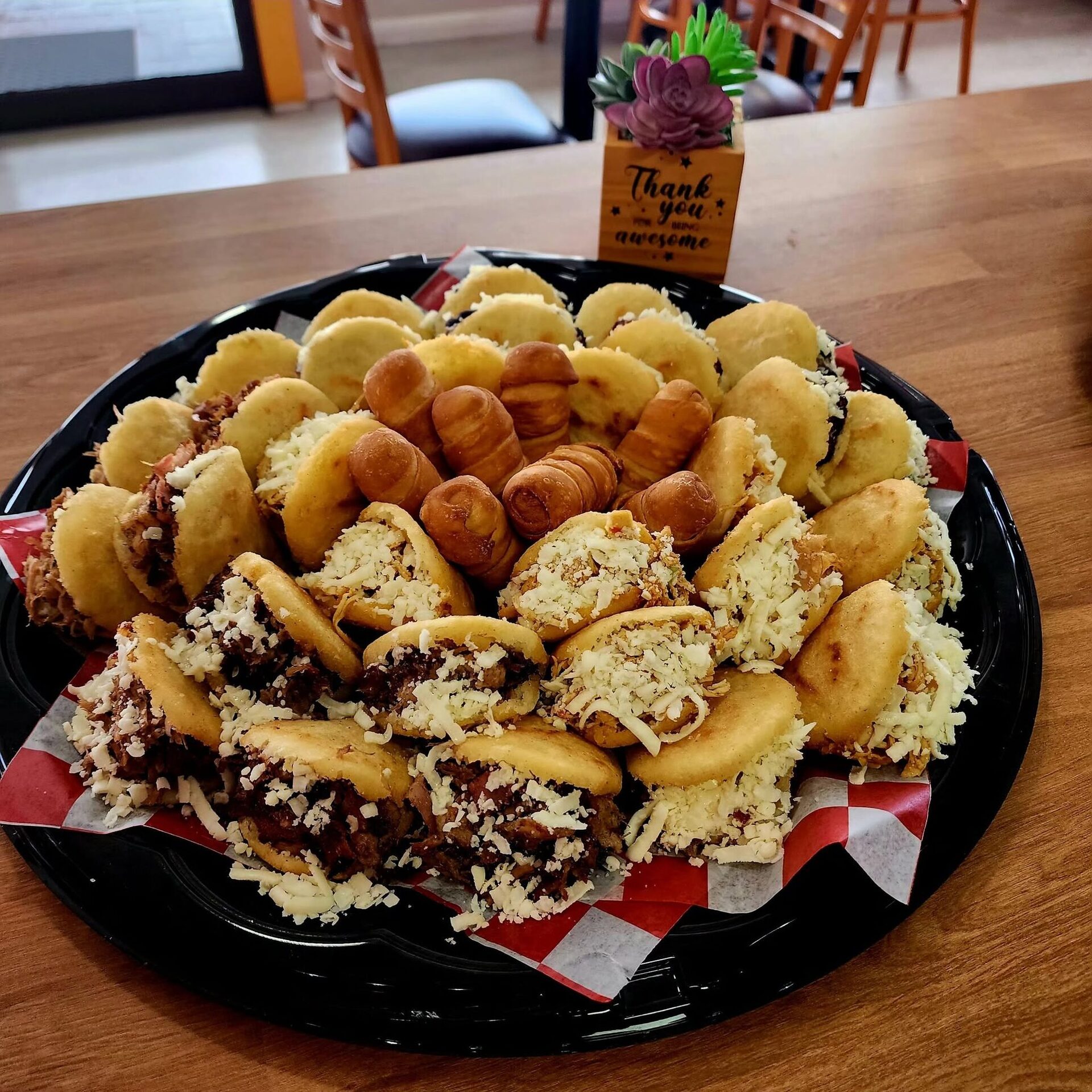 A 1Chick 1Bro platter of mini arepas and tequeños on red-check paper