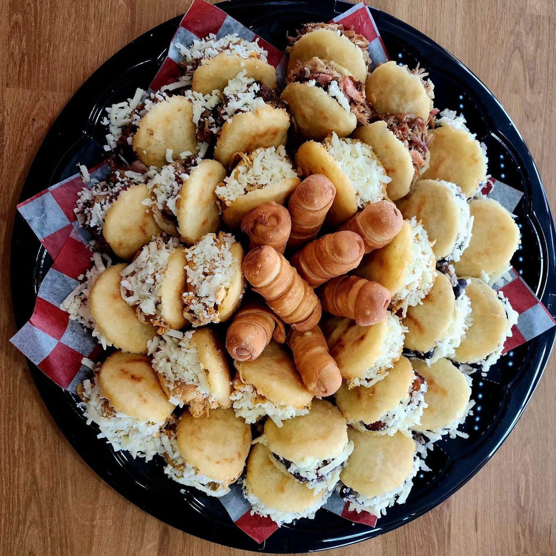 Overhead view of a platter of mini arepas with tequeños at the center